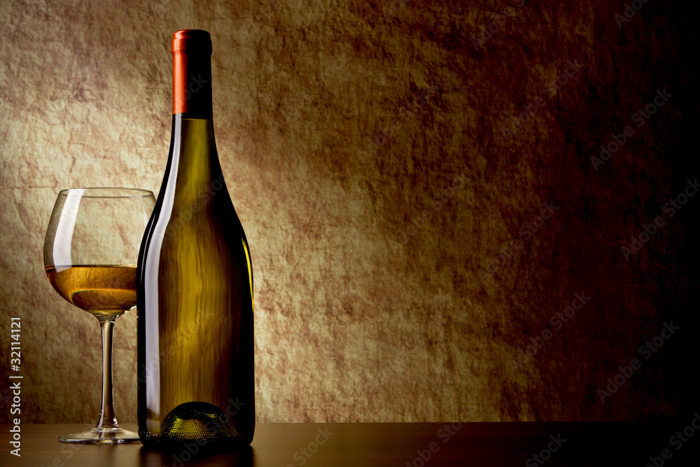 bottle with white wine and glass on a old stone. bottle in the f