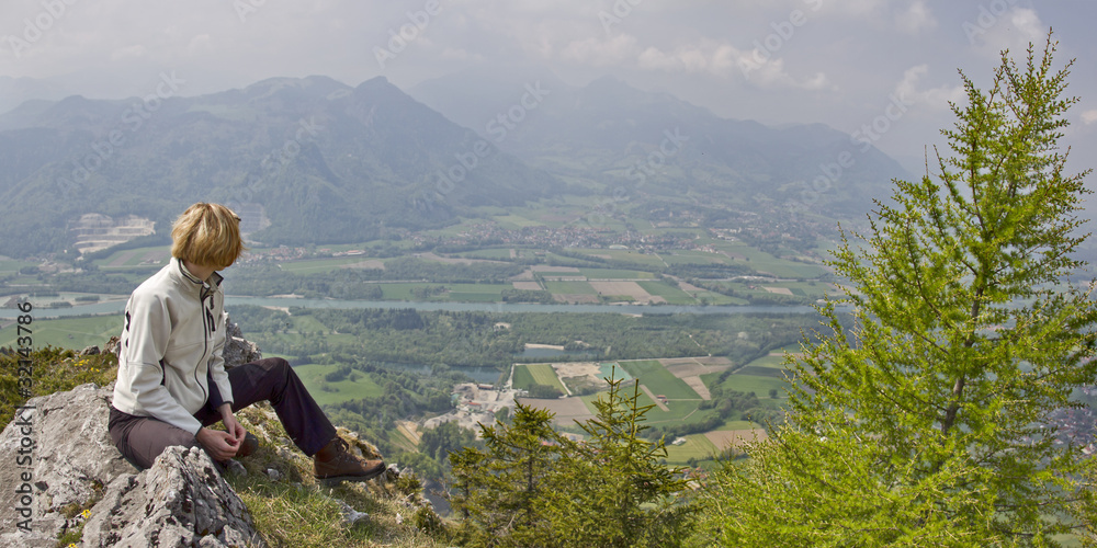 Naklejka premium frau sitzt auf gipfel in oberbayern und schaut ins inntal