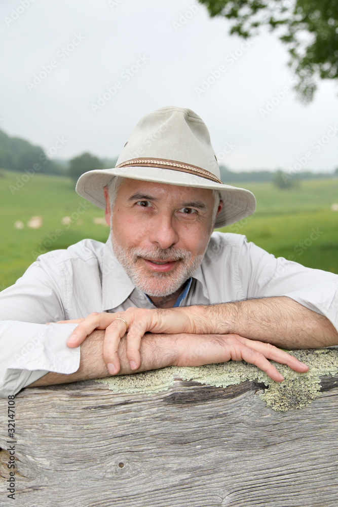 Fototapeta premium Farmer leaning on farmland fence