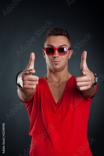 Fashion man with sunglasses pointing at the camera, studio shot