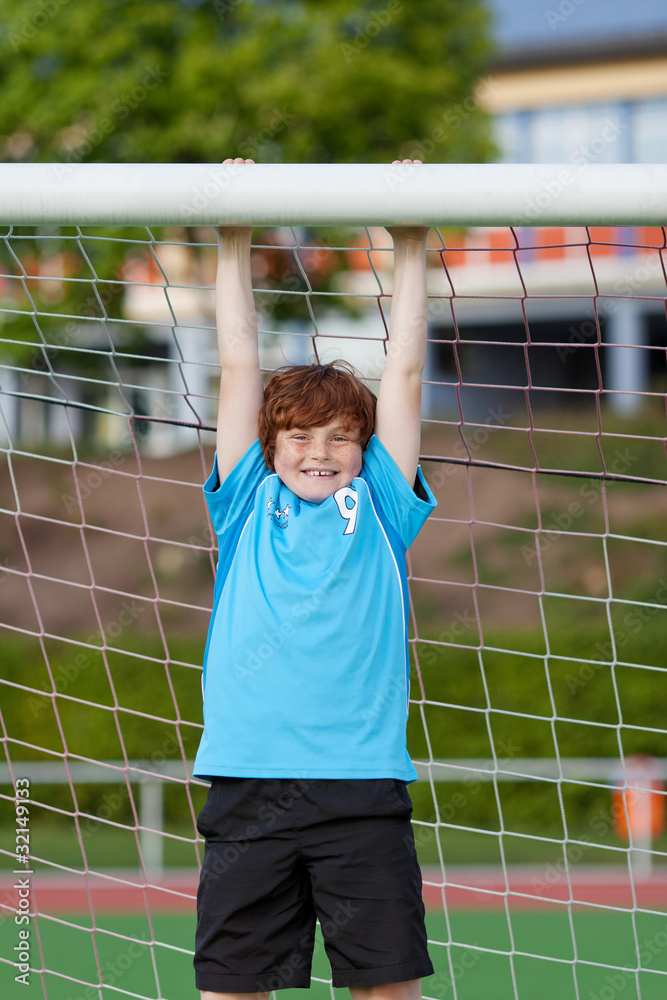 Fototapeta premium starker junge hängt am fußballtor