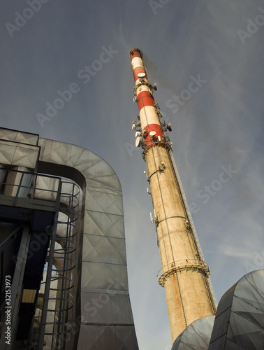 a tall chimney with smoke visible against the blue sky photo