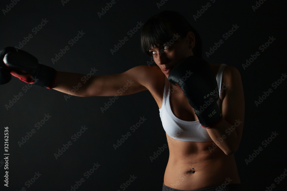 Beautiful young woman boxing in dark