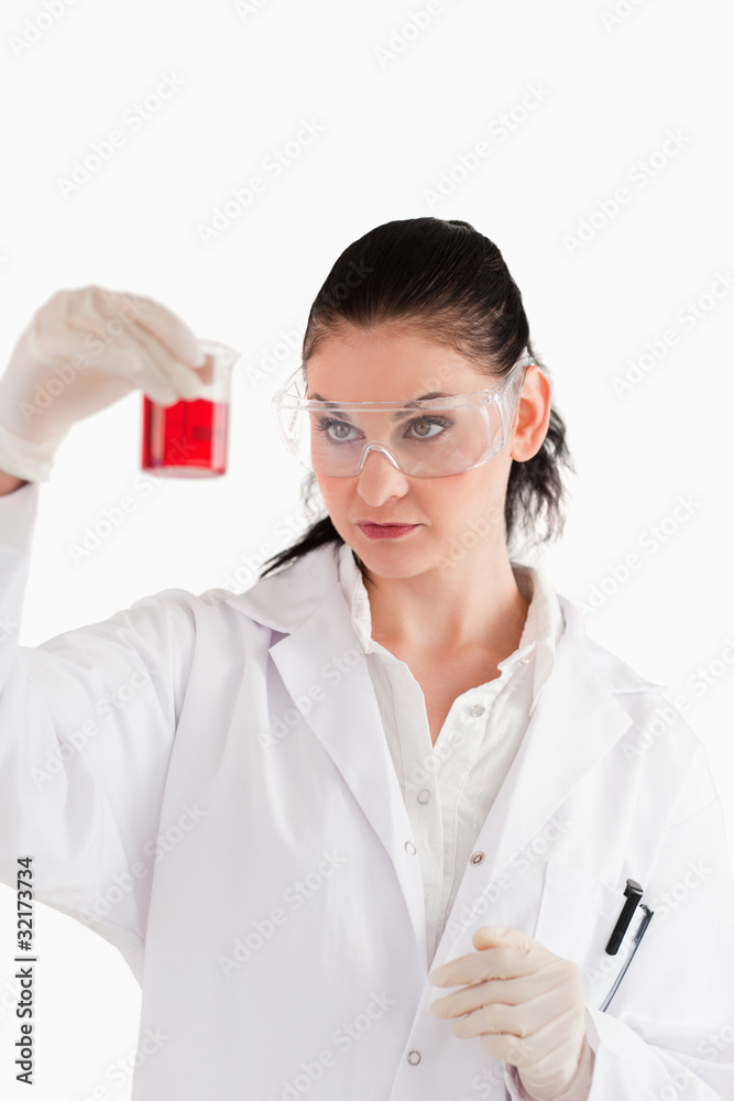 Dark-haired scientist conducting an experiment looking at a red Dark-haired scientist conducting an experiment looking at a red