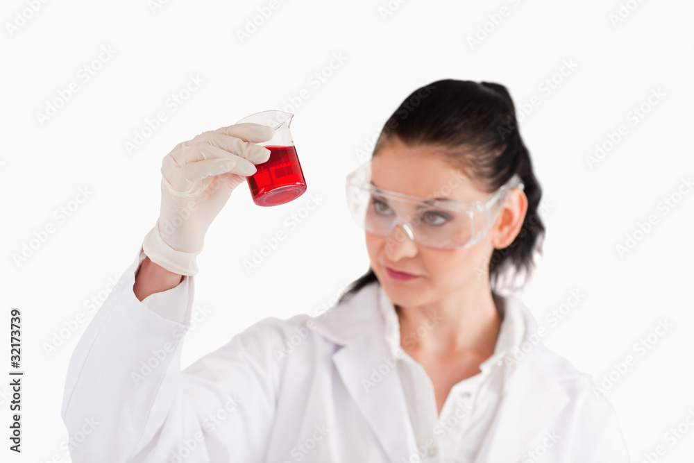 Isolated scientist looking at a red beaker Isolated scientist looking at a red beaker