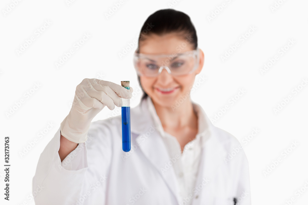 Smiling female scientist looking at a blue test tube Smiling female scientist looking at a blue test tube