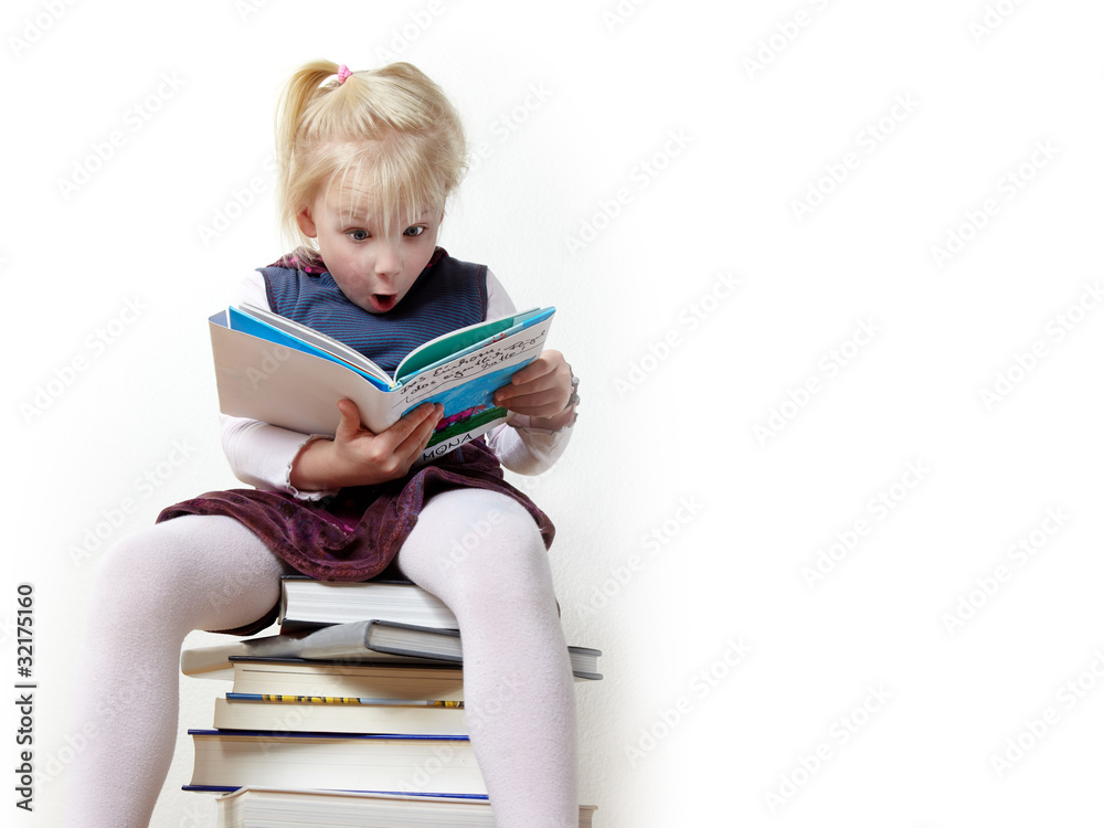 Surprised girl reading a book and sitting on a pile of books Surprised girl reading a book and sitting on a pile of books