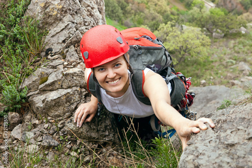 Portrait of cheerful female climber ascending a rock