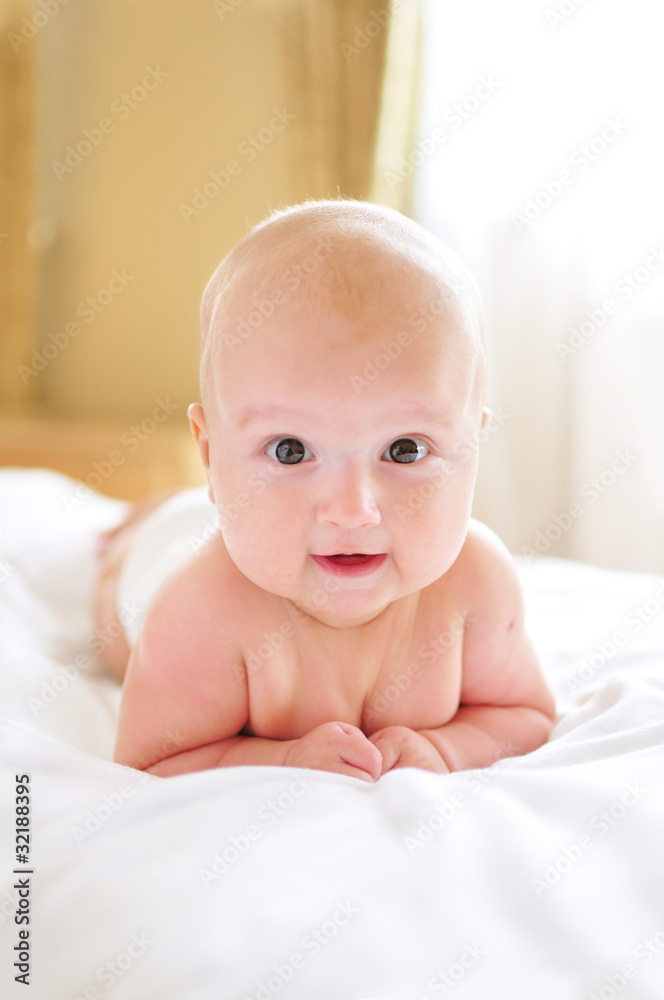 Cute baby lying on belly in bed Cute baby lying on belly in bed