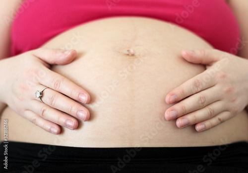 Pregnant woman hugs her belly