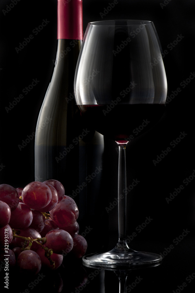 Fototapeta premium Glass of red wine with bottle and grapes