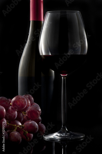Glass of red wine with bottle and grapes