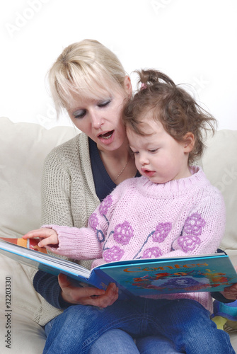 Mother and daughter sitting in living room reading book