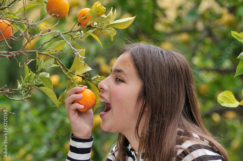 Girl eating an orange from the tree