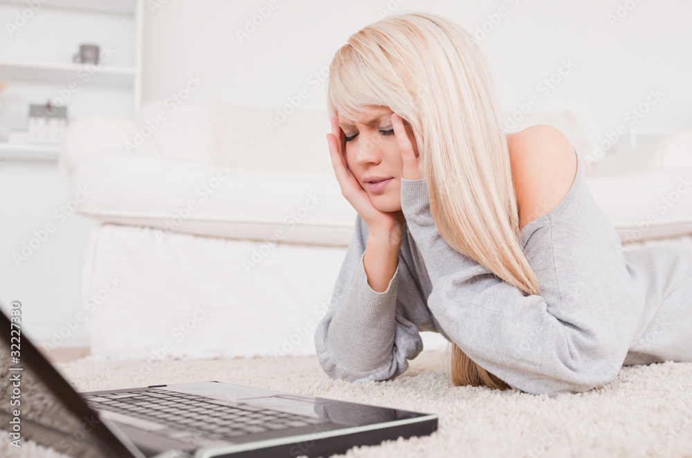 Pretty concentrated woman relaxing on laptop lying on a carpet Pretty concentrated woman relaxing on laptop lying on a carpet