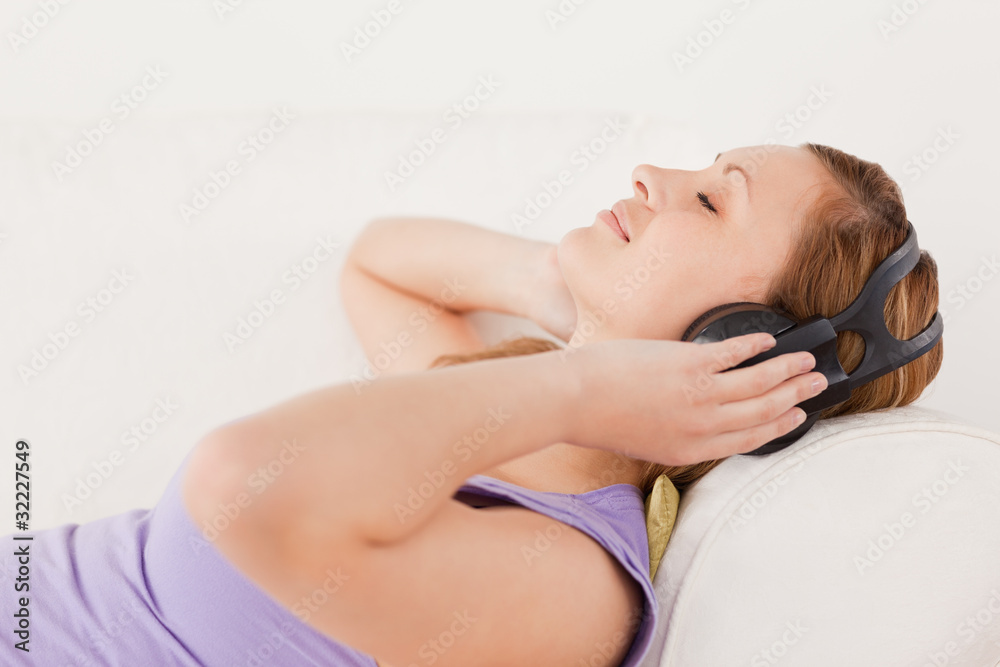 Obraz premium Lovely blond-haired woman listening to music lying on the sofa