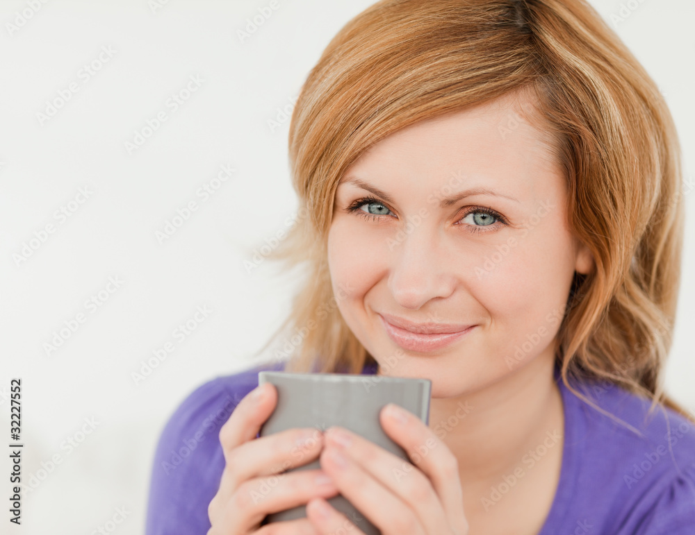 Portrait of a good looking red-haired woman holding a cup of cof