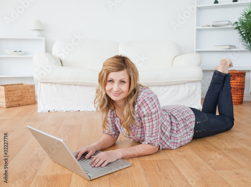 Cute woman looking at the camera while chatting on her laptop