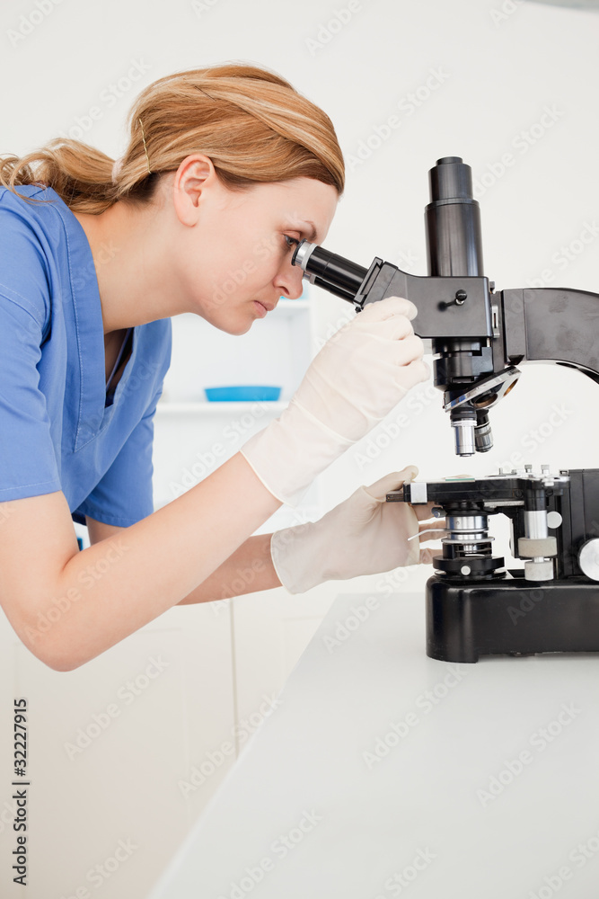 Blond-haired scientist looking through a microscope Blond-haired scientist looking through a microscope