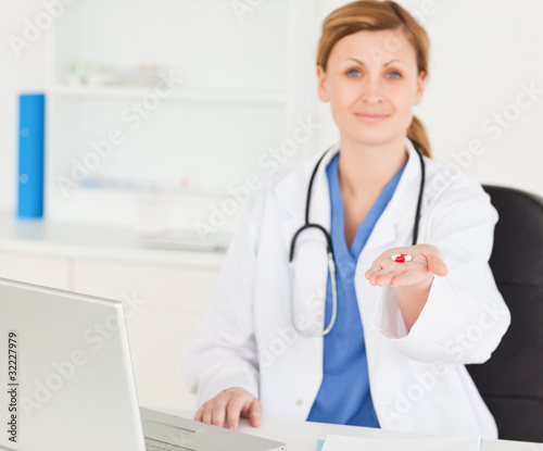 Beautiful female doctor showing pills to the camera
