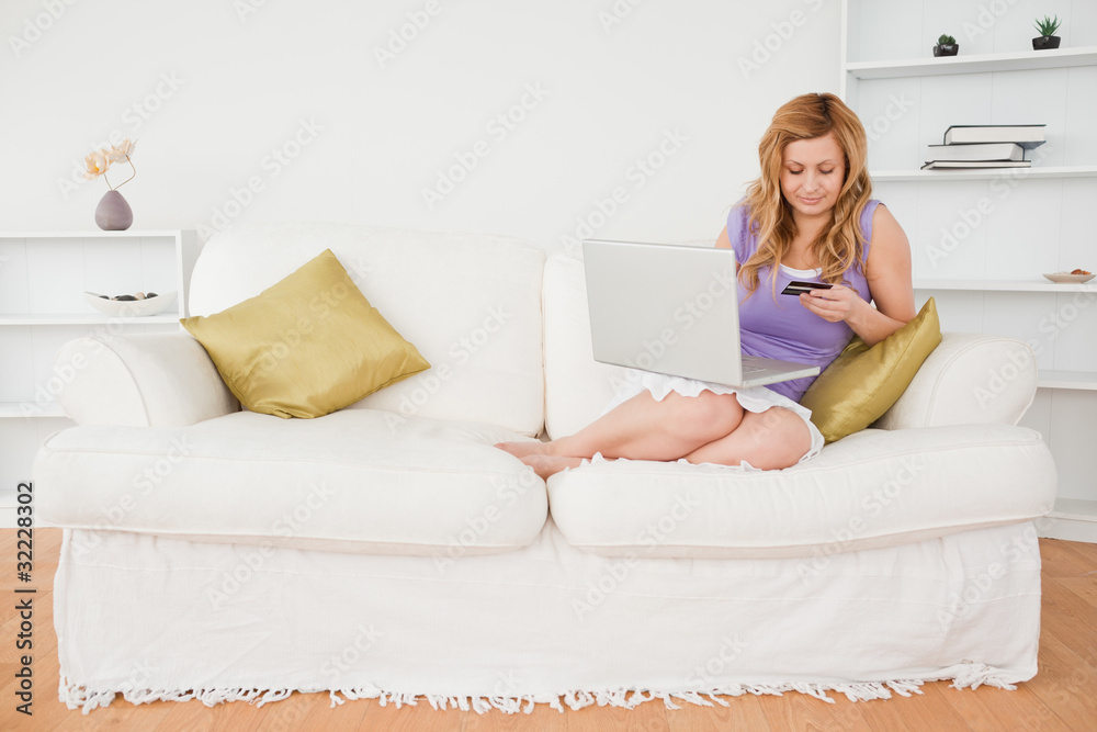 Beautiful woman sitting on a sofa is going to make a payment on Beautiful woman sitting on a sofa is going to make a payment on