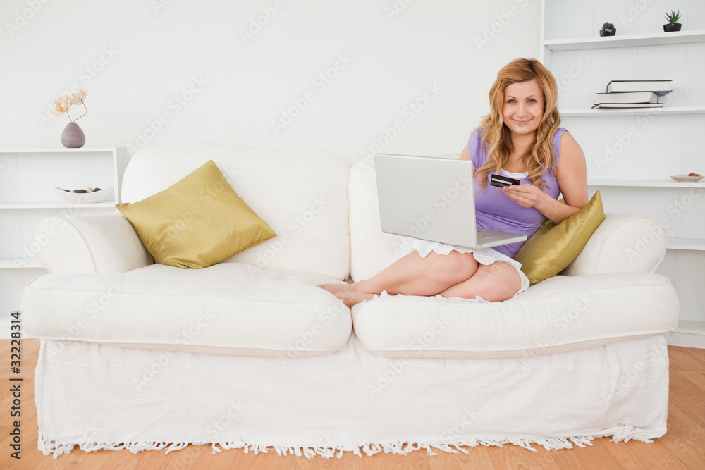 Attractive woman sitting on a sofa is going to make a payment on Attractive woman sitting on a sofa is going to make a payment on