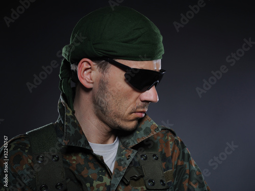 portrait of soldier in camouflage and ammunition . studio shot
