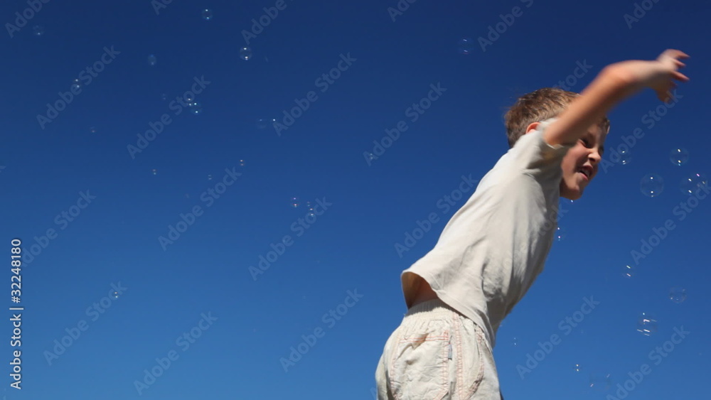 boy waving arms, knocking lot of flying to him bubbles boy waving arms, knocking lot of flying to him bubbles