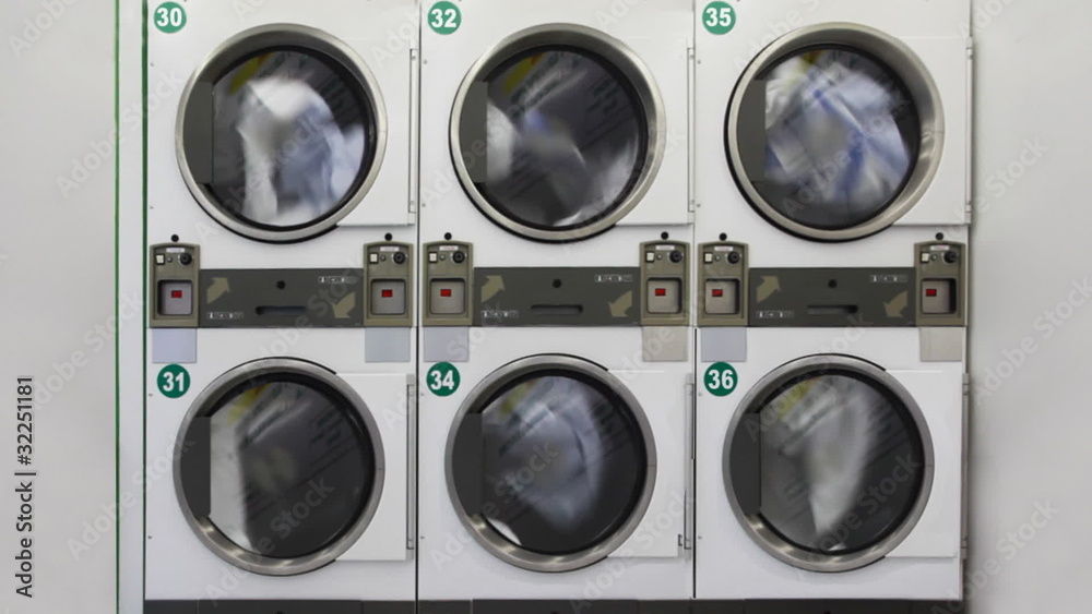 six washing machines in public laundry room with rotating drums six washing machines in public laundry room with rotating drums