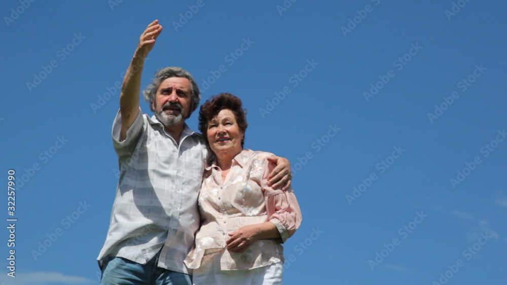 mature couple stands embrace against sky in summer mature couple stands embrace against sky in summer