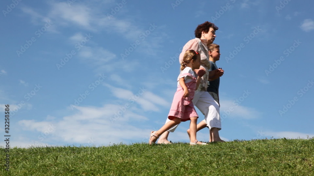boy and girl with grandmother holding hands go against sky boy and girl with grandmother holding hands go against sky