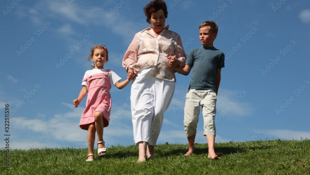 boy and girl with grandmother holding hands go by grass boy and girl with grandmother holding hands go by grass