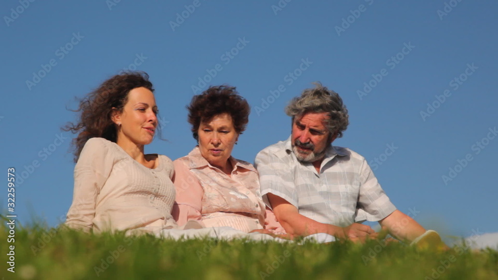 adult daughter with parents sit on grass and something talk adult daughter with parents sit on grass and something talk