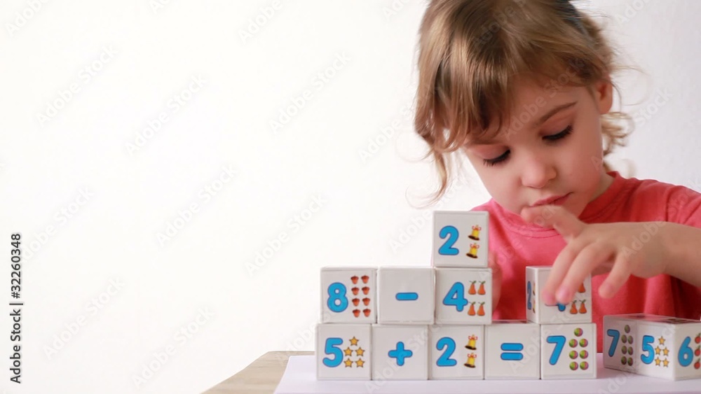 girl puts wooden bloks with numbers on desk, adds cubes girl puts wooden bloks with numbers on desk, adds cubes