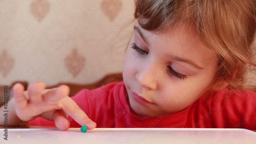 beautiful girl rolling plasticine ball on wooden table beautiful girl rolling plasticine ball on wooden table