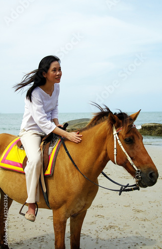 young woman riding a horse on the beach