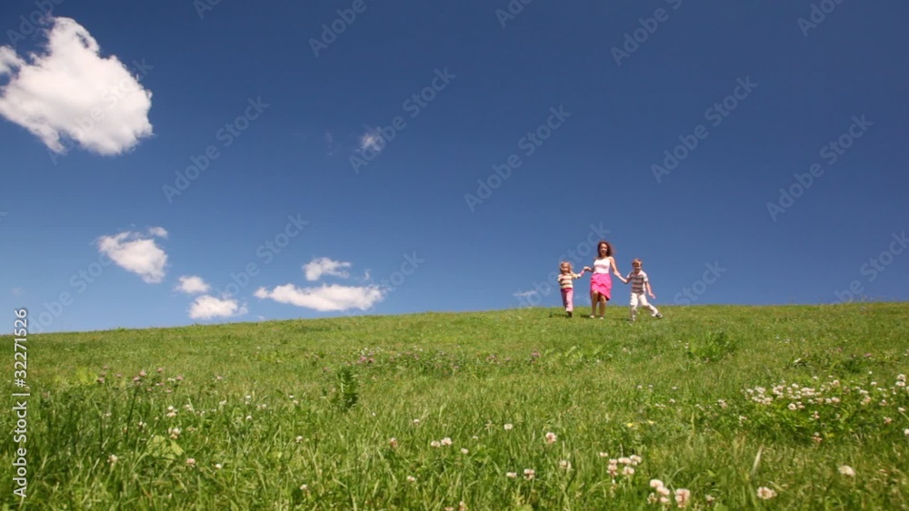 woman with children holding hands descend hill with grass woman with children holding hands descend hill with grass