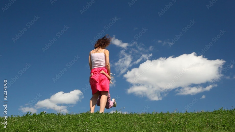 girl runs to mother on field with green grass, spinning