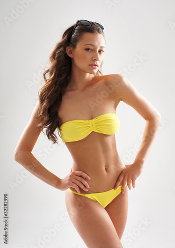 A young and sexy brunette woman in a yellow swimsuit