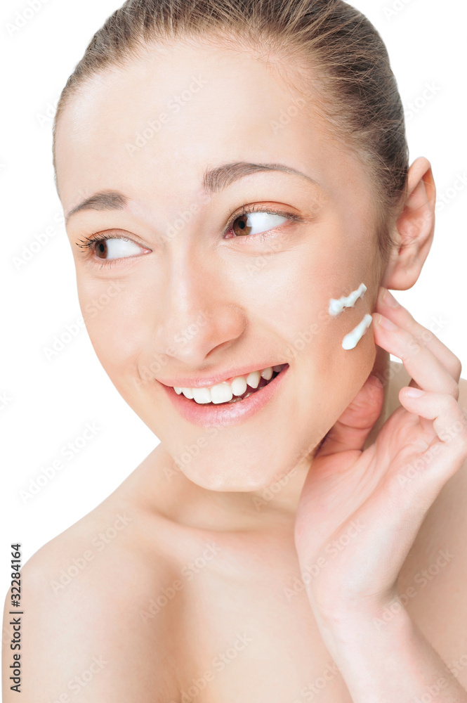 Portrait of a beautiful young woman applying cream to her face a