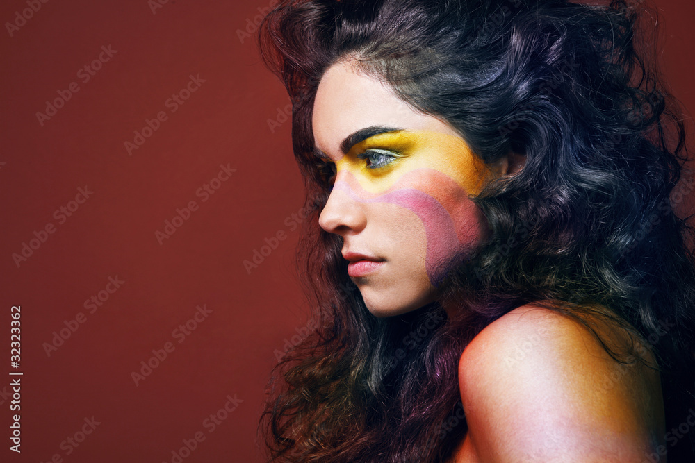 Brunette with long curly hair and colorful make-up.