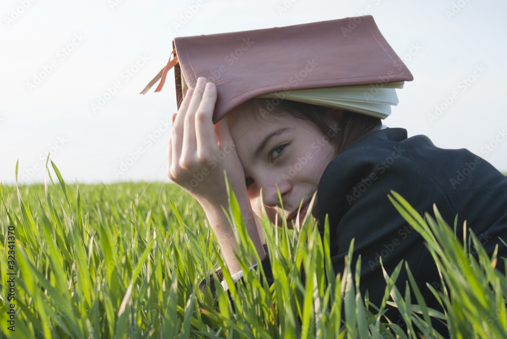 Teen girl with the Bible laying on grass