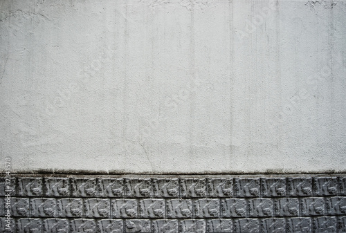 Grungy white limestone wall with spots and ceramic ornament