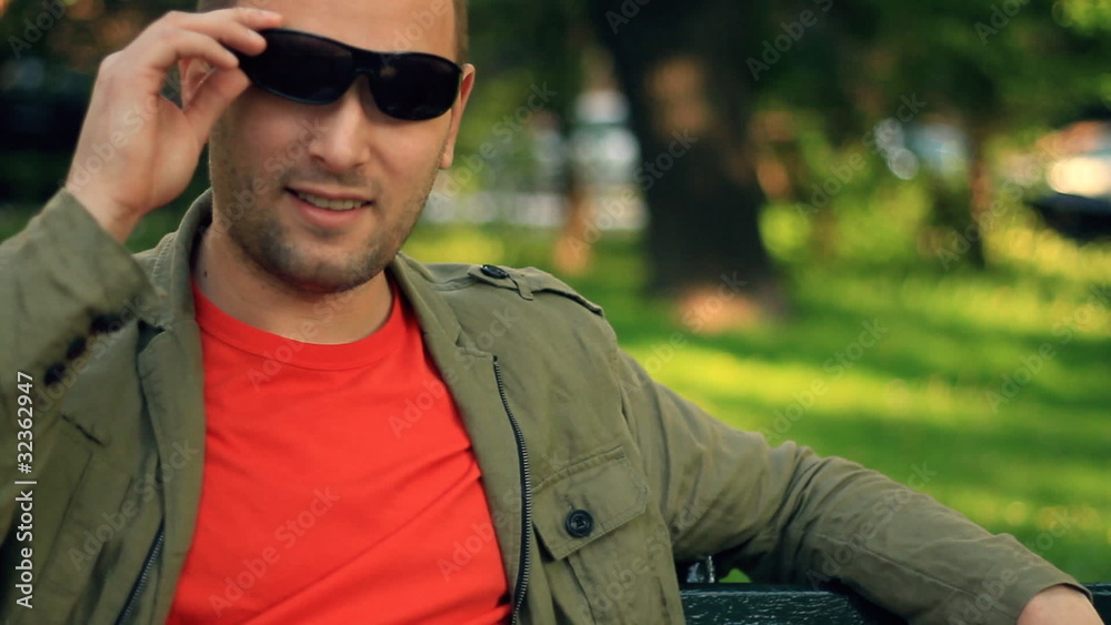 Happy handsome man relaxing on park bench, steadicam shot Happy handsome man relaxing on park bench, steadicam shot