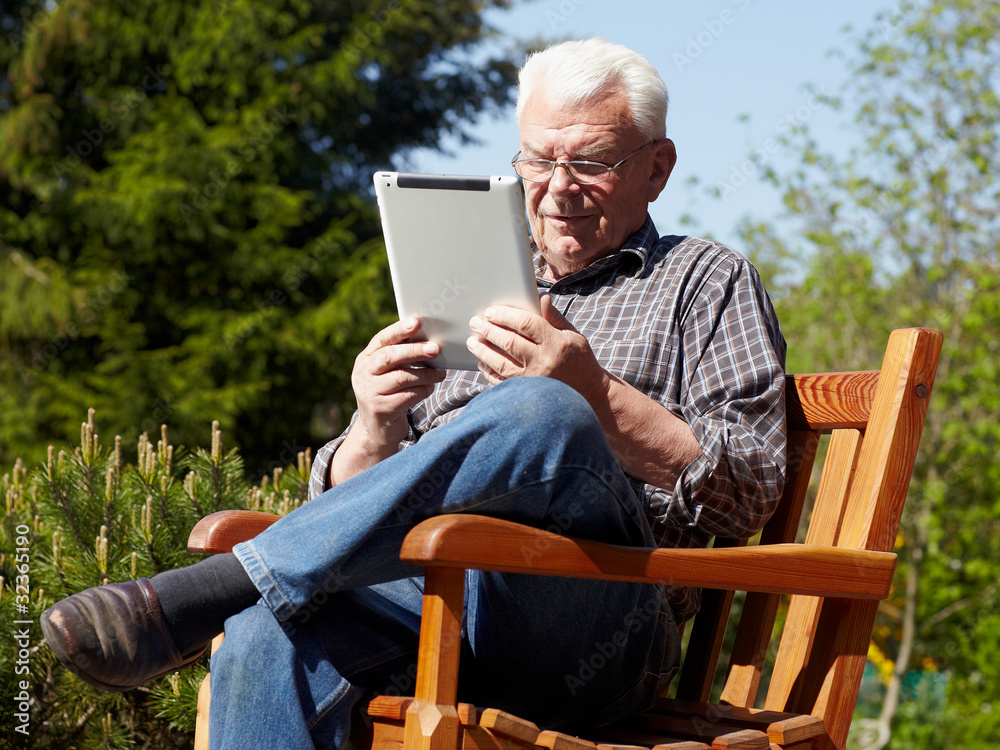 Old handsome grandfather using touchpad e-book reader Old handsome grandfather using touchpad e-book reader