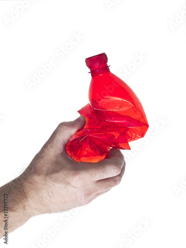 mano che impugna una bottiglia di plastica rossa schiacciata photo