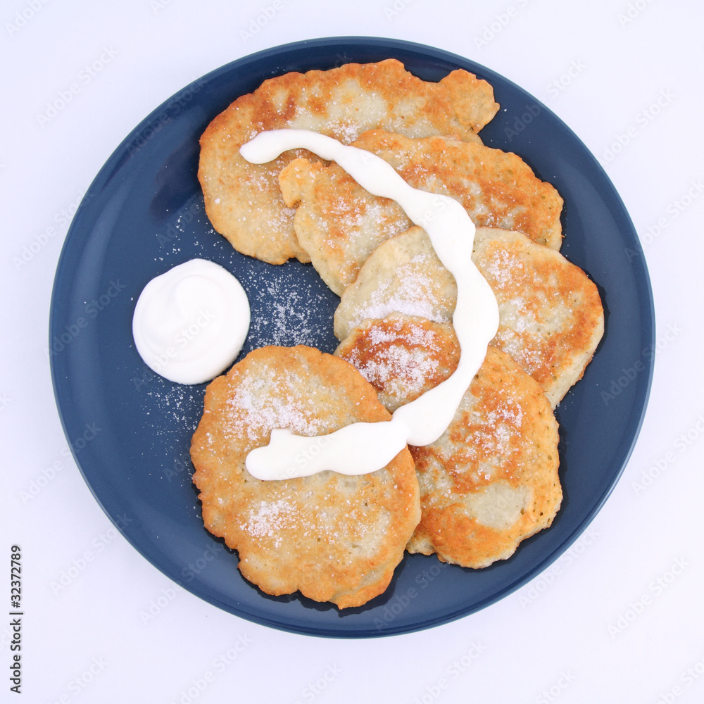 Potato pan cakes with cream and sugar on white background Potato pan cakes with cream and sugar on white background