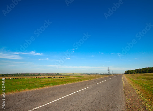 Summer landscape with rural road and cloudy sky