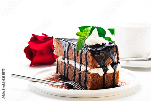 A piece of chocolate cake with vanilla cream and a rose