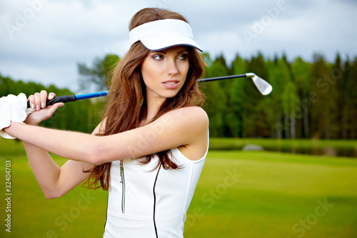 Portrait of a woman holding a golf club in her hands on a green
